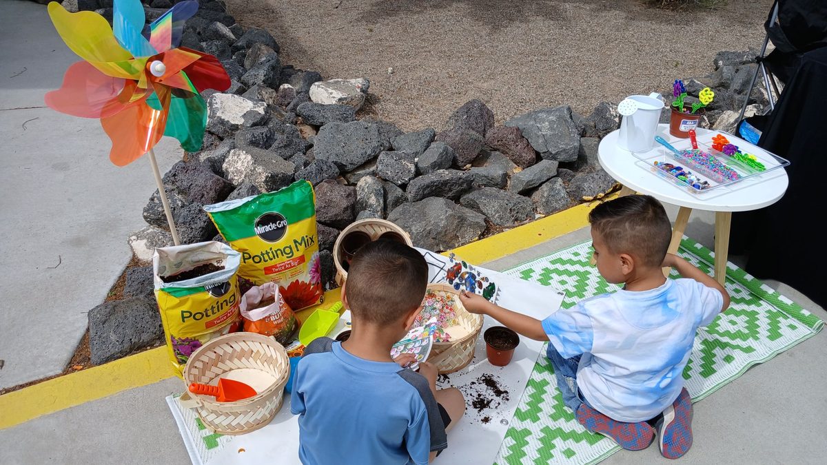 Two kids planting flowers at the NM community event