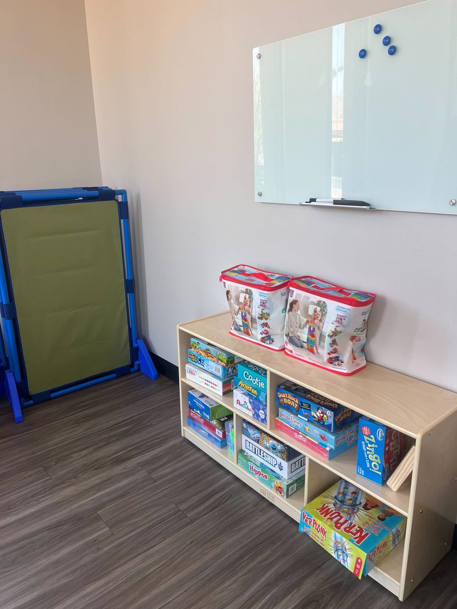 Therapy room with games shelf and whiteboard